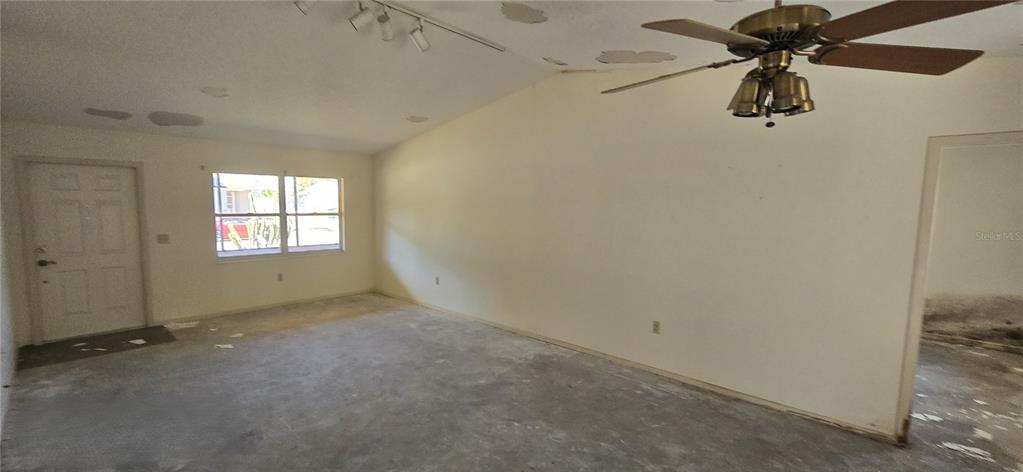 An empty living room features a vaulted ceiling, a ceiling fan, and concrete flooring — 2094 CARPETGREEN STREET, PORT CHARLOTTE, FL