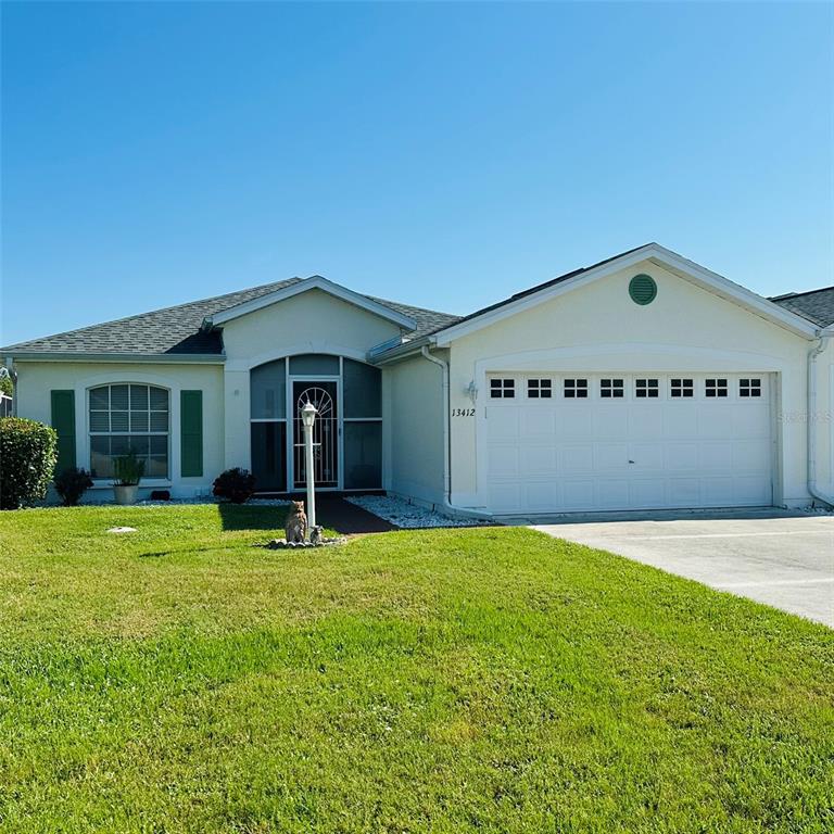 A single-story house with a white exterior, a two-car garage, and a screened front entryway — 13412 SW PEMBROKE CIRCLE N, LAKE SUZY, FL