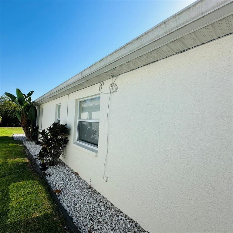The exterior of a white stucco house features a window, a gutter, and loose wires — 13412 SW PEMBROKE CIRCLE N, LAKE SUZY, FL