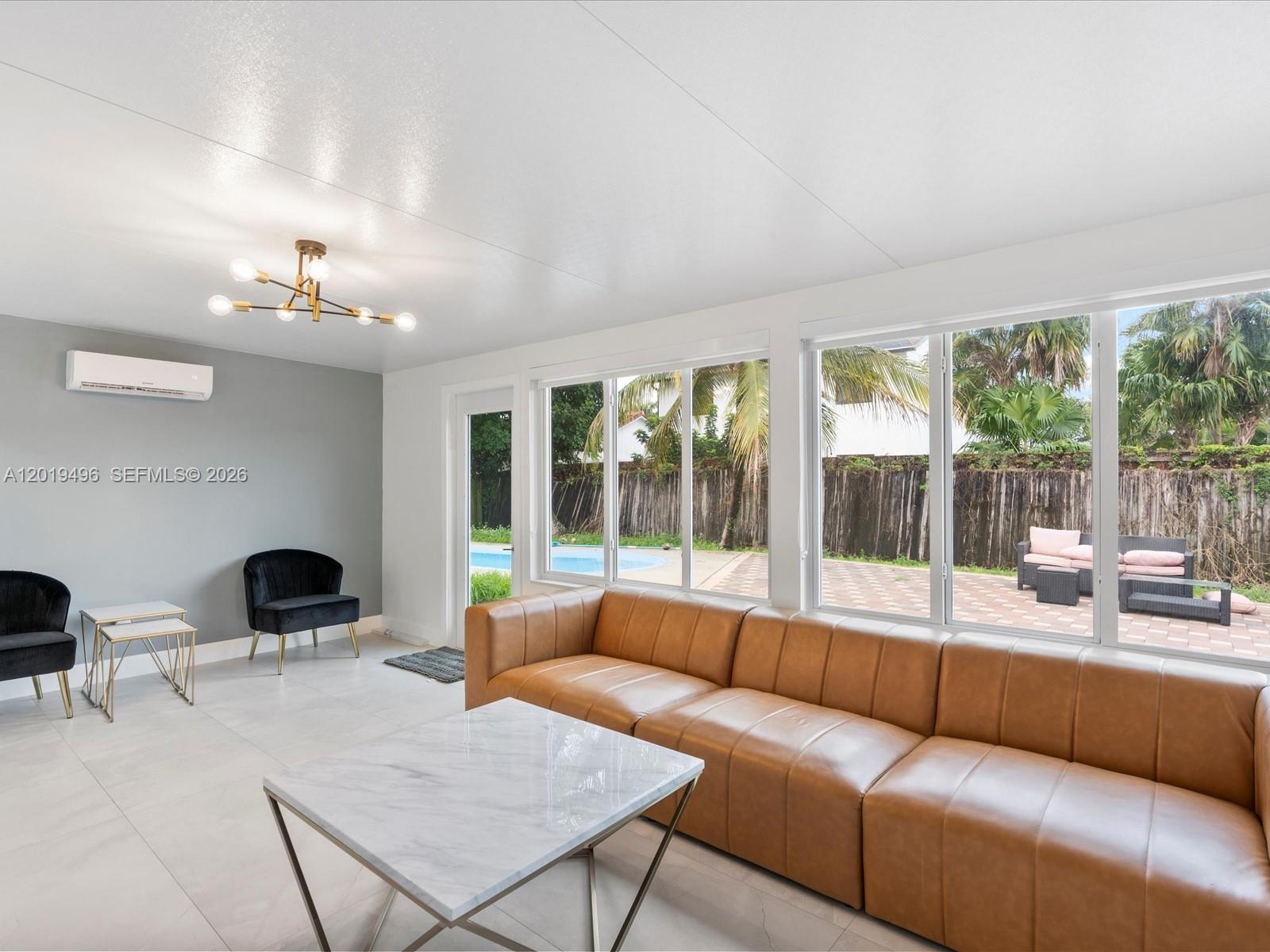 A living room features a tan leather sofa, marble coffee table, and views of a pool — 5731 SW 54th Ter, Davie FL 33314, DAVIE, FL