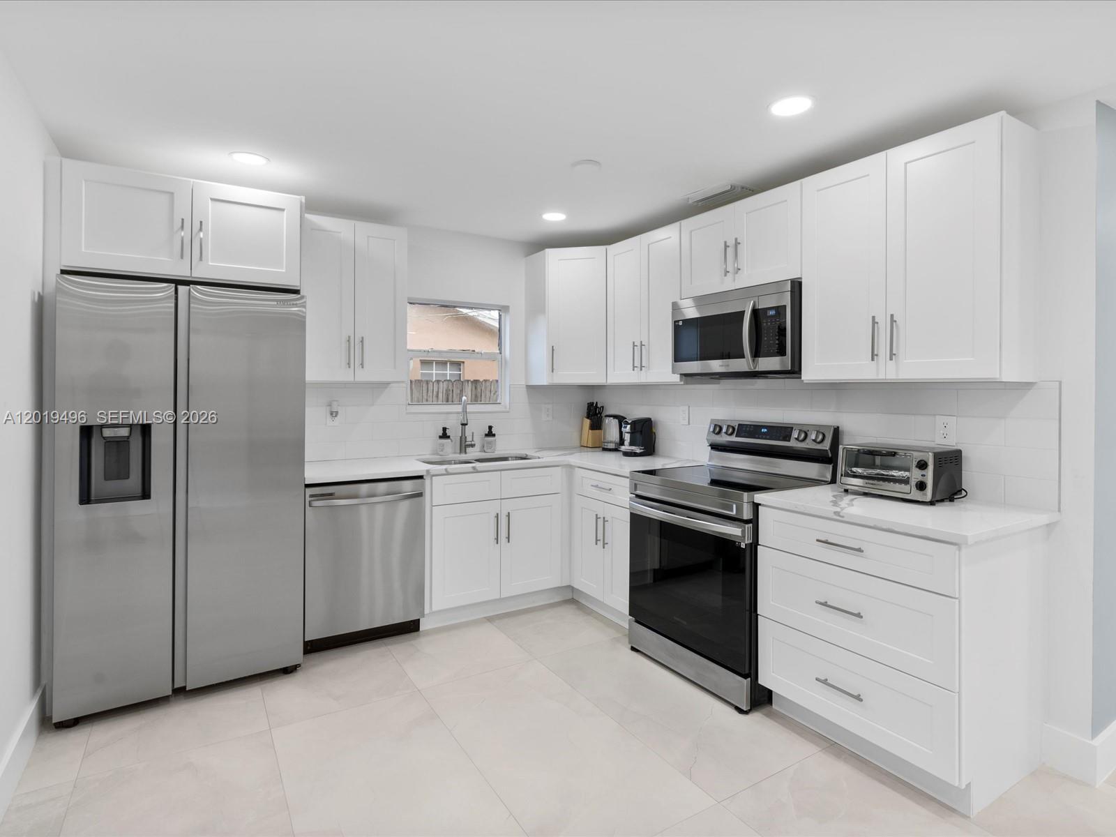 A kitchen features white cabinets, stainless steel appliances, and light-colored tile flooring — 5731 SW 54th Ter, Davie FL 33314, DAVIE, FL