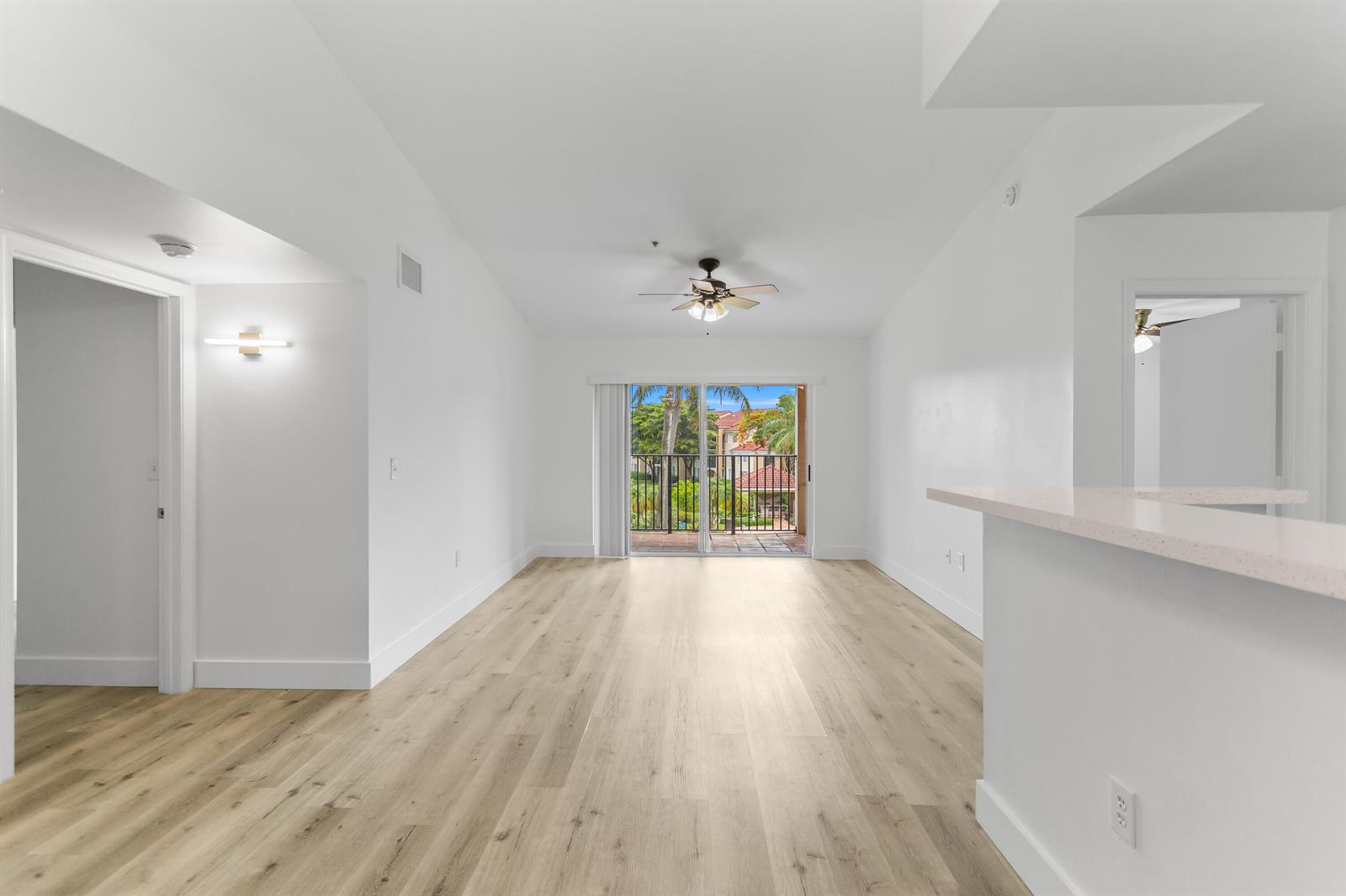 An empty living room with light wood flooring, a ceiling fan, and a sliding glass door — 2113 Renaissance Boulevard # 306, Miramar FL 33025, MIRAMAR, FL