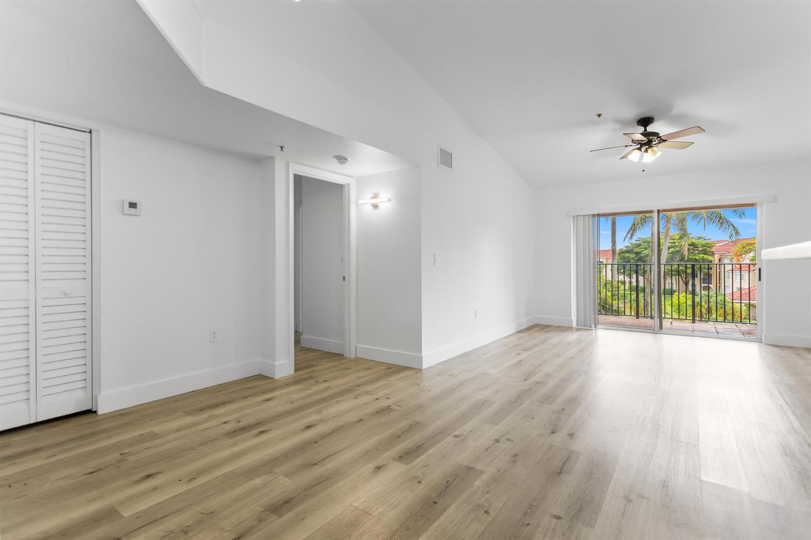 An empty room with light wood-look flooring, white walls, a ceiling fan, and a balcony — 2113 Renaissance Boulevard # 306, Miramar FL 33025, MIRAMAR, FL
