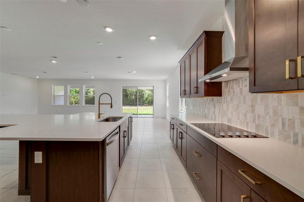 A modern kitchen features dark wood cabinets, white countertops, a large island, and tile flooring — 3057 WATER CLOVER COURT, APOPKA, FL