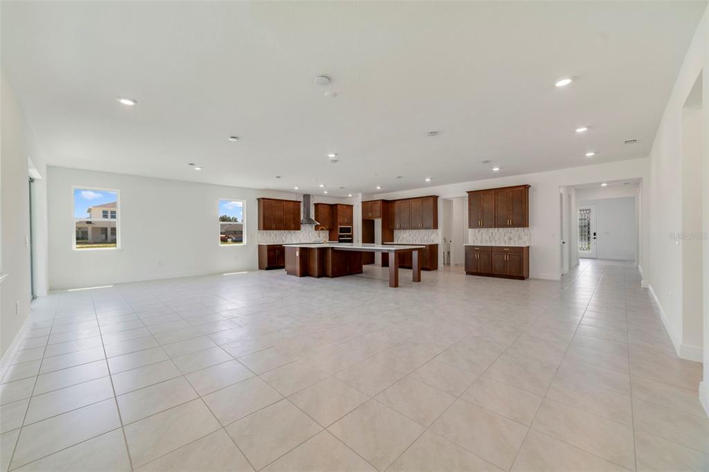 A spacious, open-concept kitchen features dark wood cabinetry, a large central island, and tile flooring — 3057 WATER CLOVER COURT, APOPKA, FL