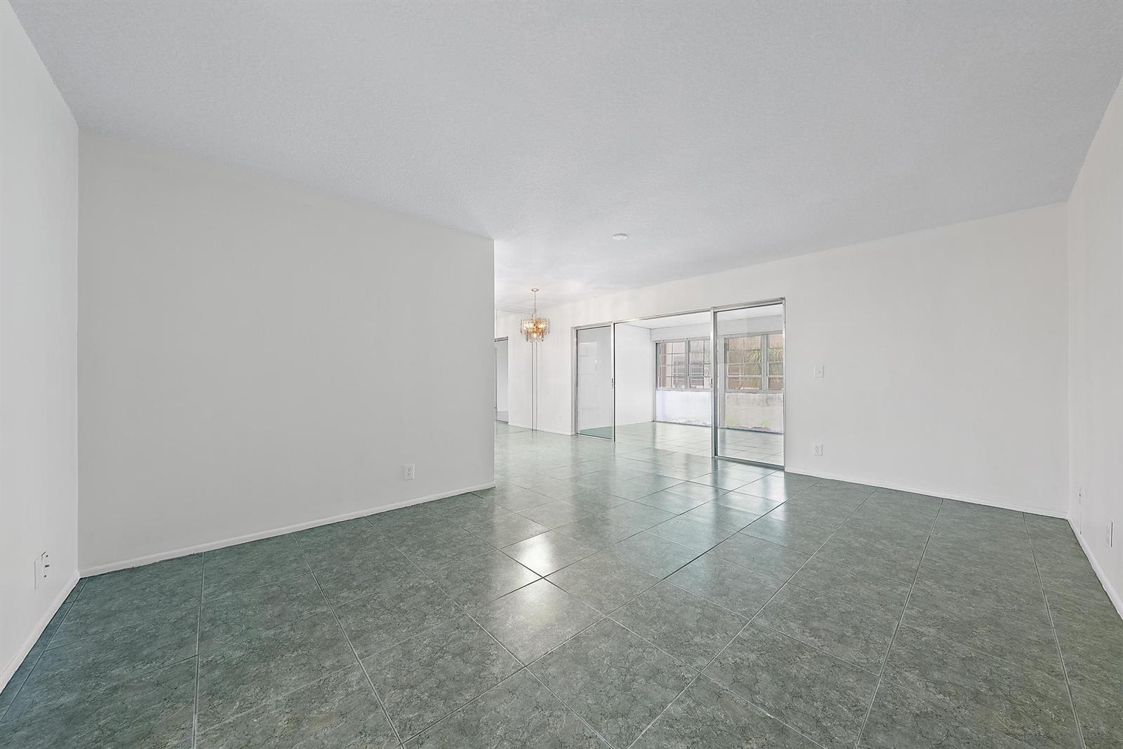 An empty living area features white walls, gray tile flooring, and sliding glass patio doors — 2638 Gately Drive E # 45, West Palm Beach FL 33415, WEST PALM BEACH, FL