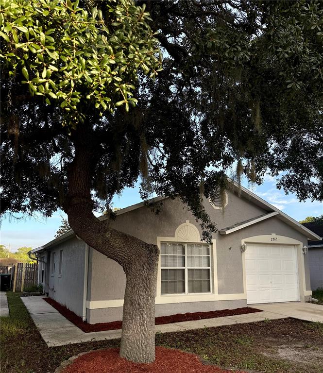 A single-story gray house with a white garage door and a large tree in front — 2212 ROSE BROOK COURT, ORLANDO, FL
