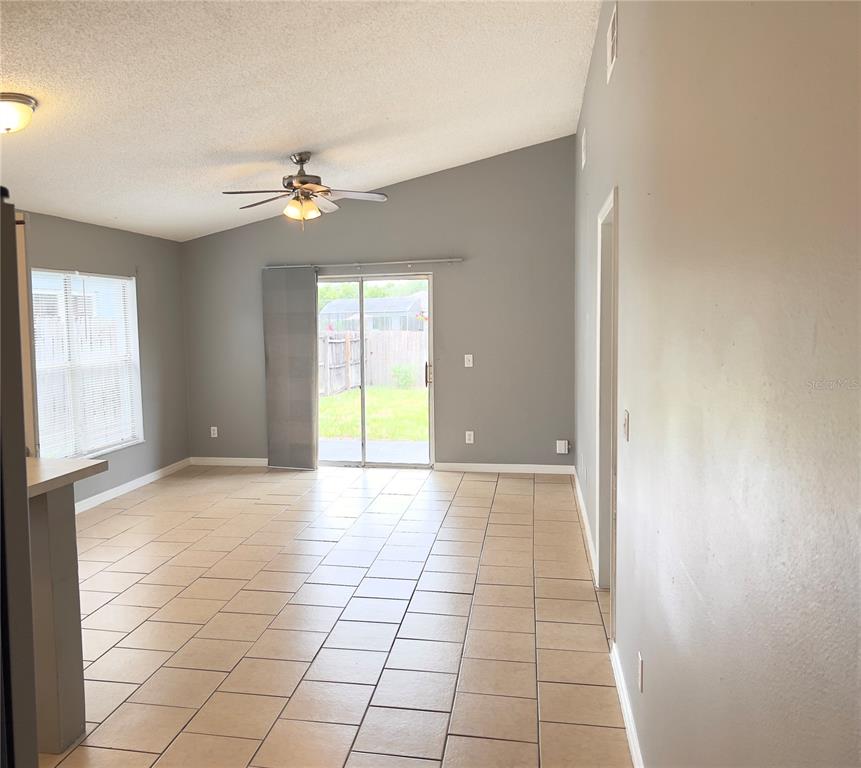 A living room with tile flooring, a vaulted ceiling, a ceiling fan, and sliding glass doors — 2212 ROSE BROOK COURT, ORLANDO, FL
