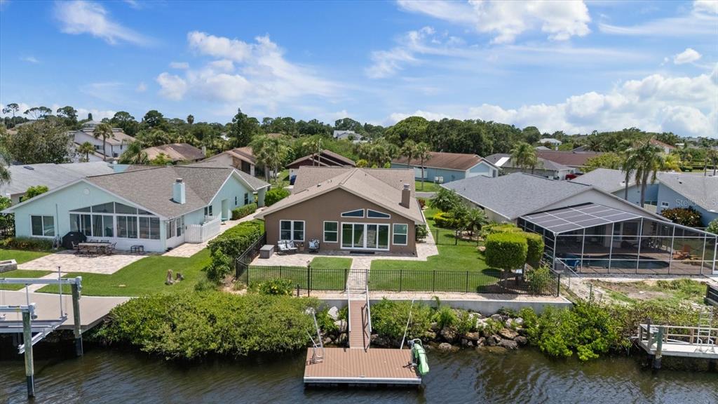 An aerial view of a waterfront house with a backyard, dock, and pool enclosure — 4537 RICKOVER COURT, NEW PORT RICHEY, FL