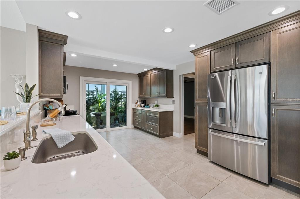A kitchen with dark wood cabinets, stainless steel appliances, and a sliding glass door — 4537 RICKOVER COURT, NEW PORT RICHEY, FL