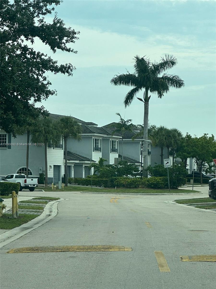 A view of a residential street with townhouses, palm trees, and a keep right sign — 3593 NW 13th St # 3593, Lauderhill FL 33311, LAUDERHILL, FL