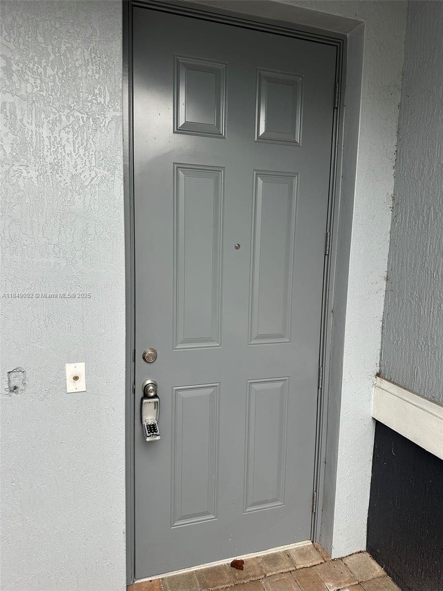 A gray six-panel door with a digital keypad lock is set into a stucco wall — 3593 NW 13th St # 3593, Lauderhill FL 33311, LAUDERHILL, FL