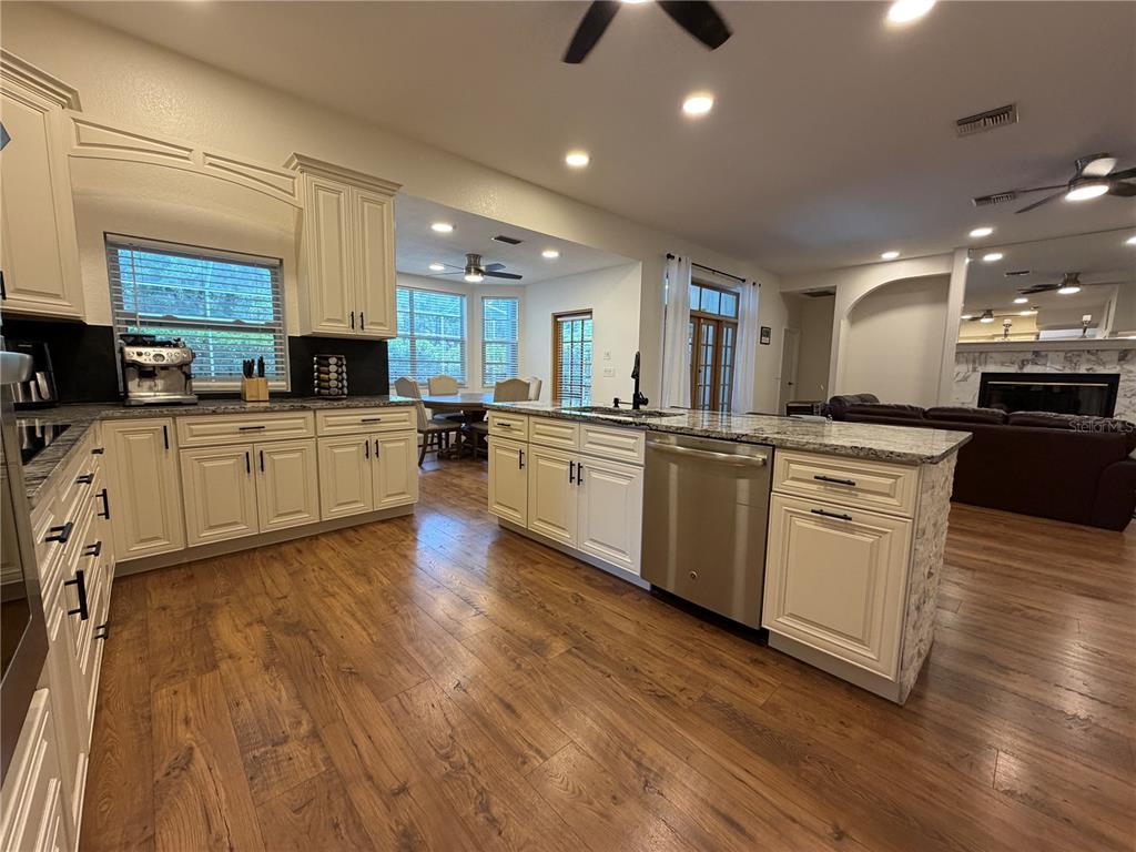 A kitchen features white cabinets, granite countertops, stainless steel appliances, and wood-look flooring — 2966 POST ROCK COURT, TARPON SPRINGS, FL