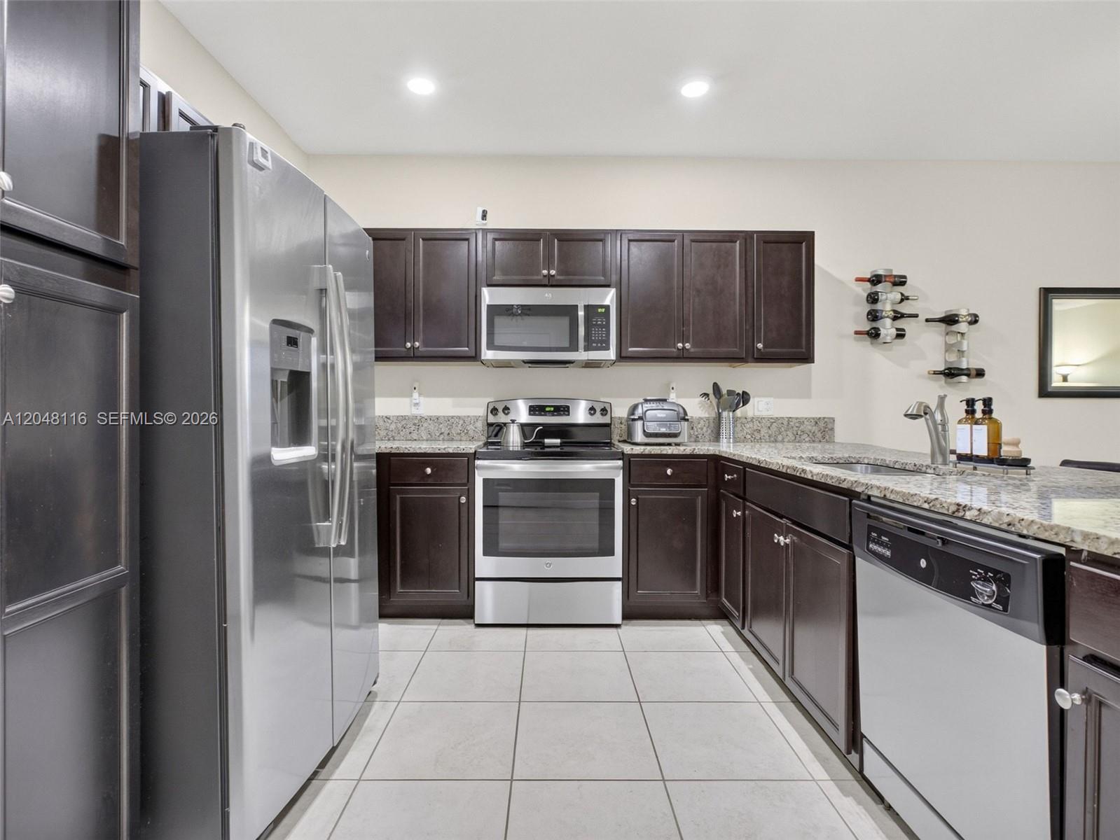 A kitchen features dark wood cabinets, stainless steel appliances, and granite countertops — 5918 NW 56th Pl, Tamarac FL 33319, TAMARAC, FL