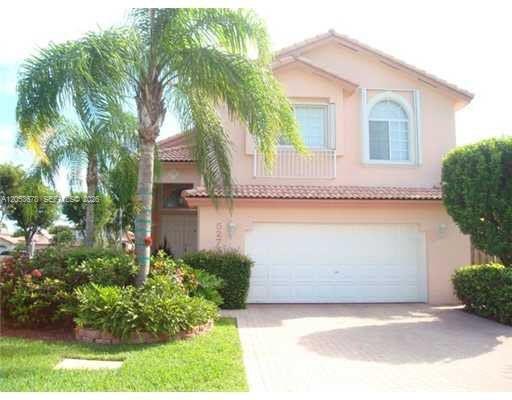 A two-story peach-colored house with a two-car garage, a palm tree, and landscaped bushes — 5273 NW 113th Ave, Doral FL 33178, DORAL, FL