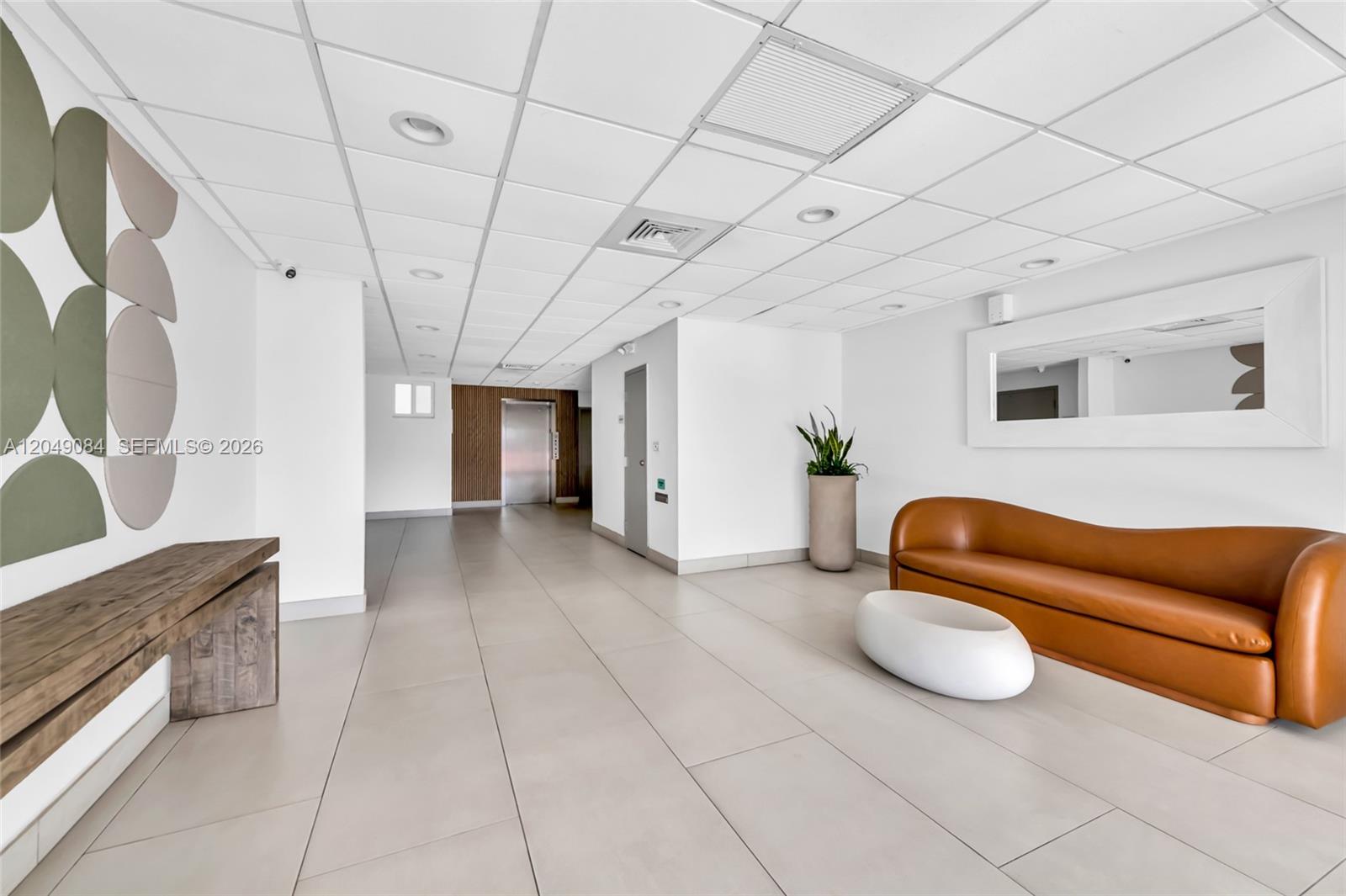 A modern lobby features a brown leather sofa, white coffee table, and wood accent wall — 1666 West Ave # 404, Miami Beach FL 33139, MIAMI BEACH, FL