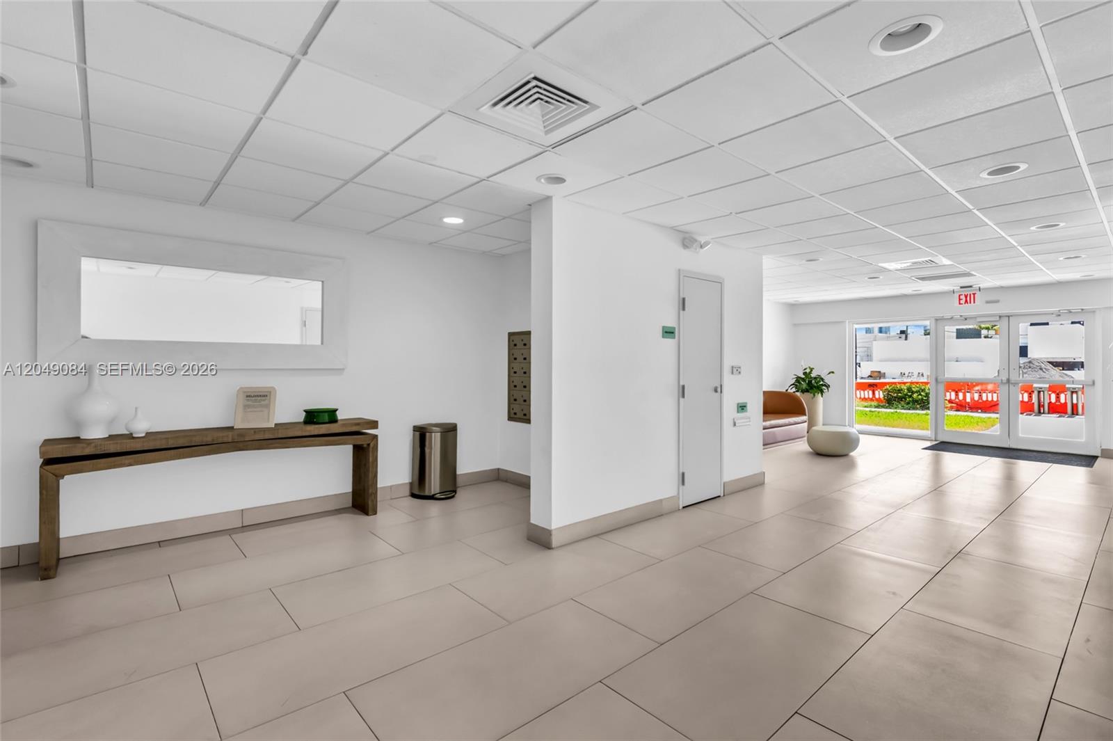 A bright lobby features a console table, a mirror, tiled floors, and glass exit doors — 1666 West Ave # 404, Miami Beach FL 33139, MIAMI BEACH, FL