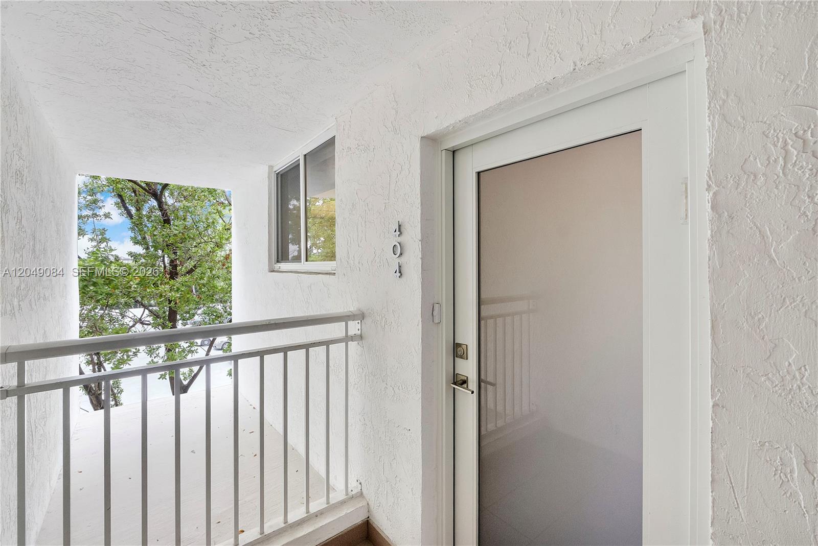 A white exterior balcony features a glass-paneled door marked with the number 404 — 1666 West Ave # 404, Miami Beach FL 33139, MIAMI BEACH, FL