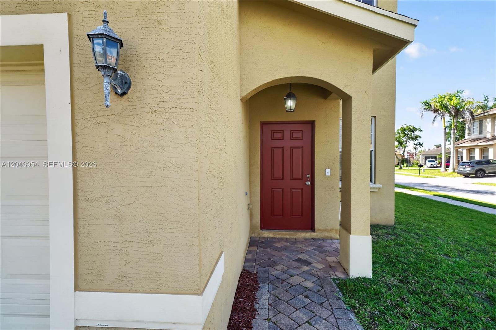 The exterior of a house features a red front door, a stone walkway, and stucco walls — 9317 Natures Way, Fort Pierce FL 34945, FORT PIERCE, FL