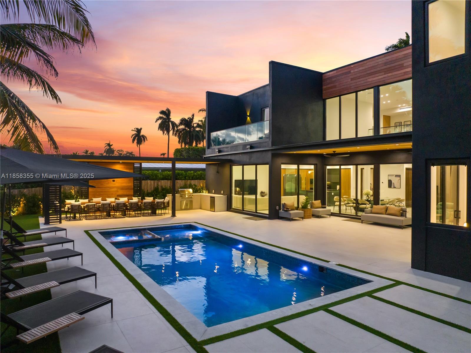 A modern two-story house with a pool, outdoor kitchen, and patio at sunset — 1960 NE 197th Ter, Miami FL 33179, MIAMI, FL