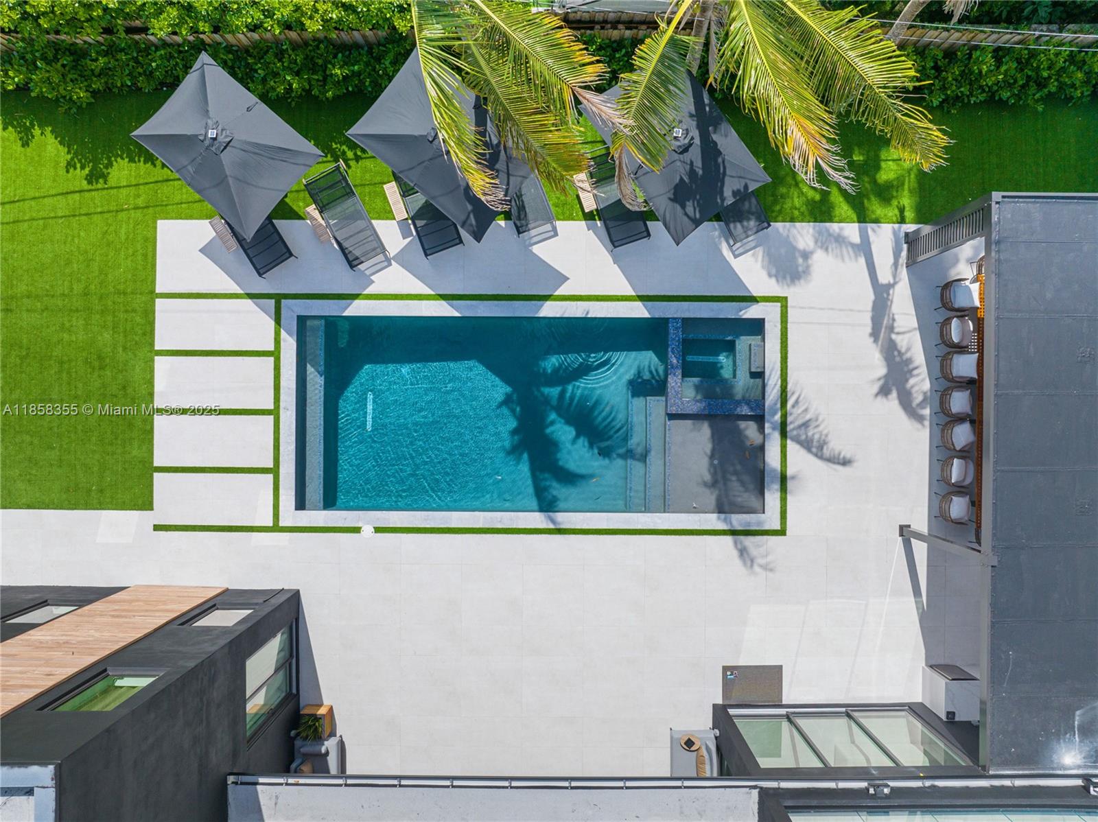 An aerial view shows a rectangular swimming pool with a spa, lounge chairs, and umbrellas — 1960 NE 197th Ter, Miami FL 33179, MIAMI, FL