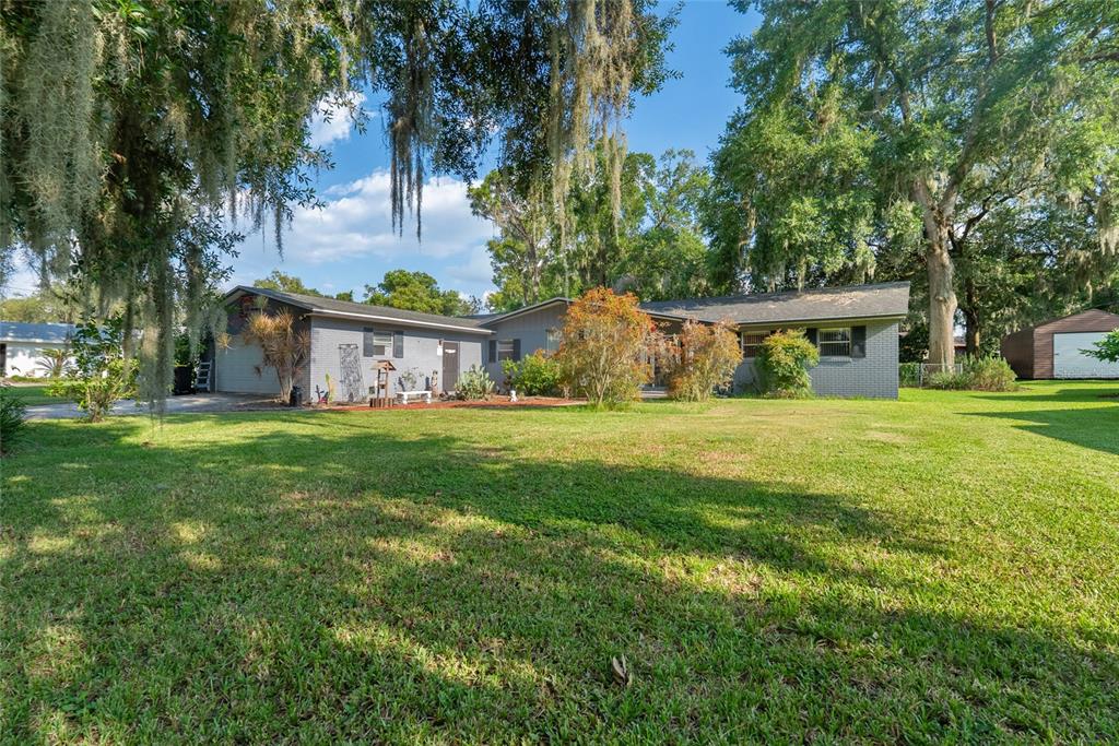 A single-story gray brick house with a large lawn and mature trees with Spanish moss — 306 GRIMES DRIVE, AUBURNDALE, FL