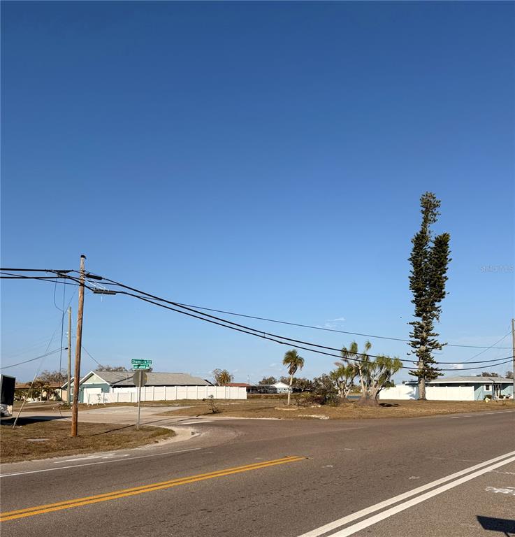 A corner lot with a street sign, utility poles, and palm trees under a clear sky — 303 SHAMROCK BOULEVARD, VENICE, FL