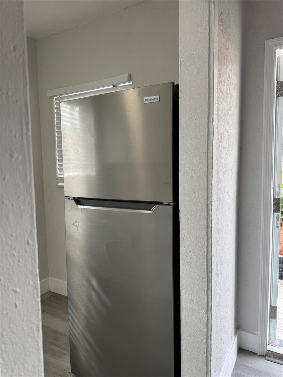 A stainless steel top-freezer refrigerator is situated in a recessed alcove near a window — 731 NW 56th Street, Miami FL 33127, MIAMI, FL