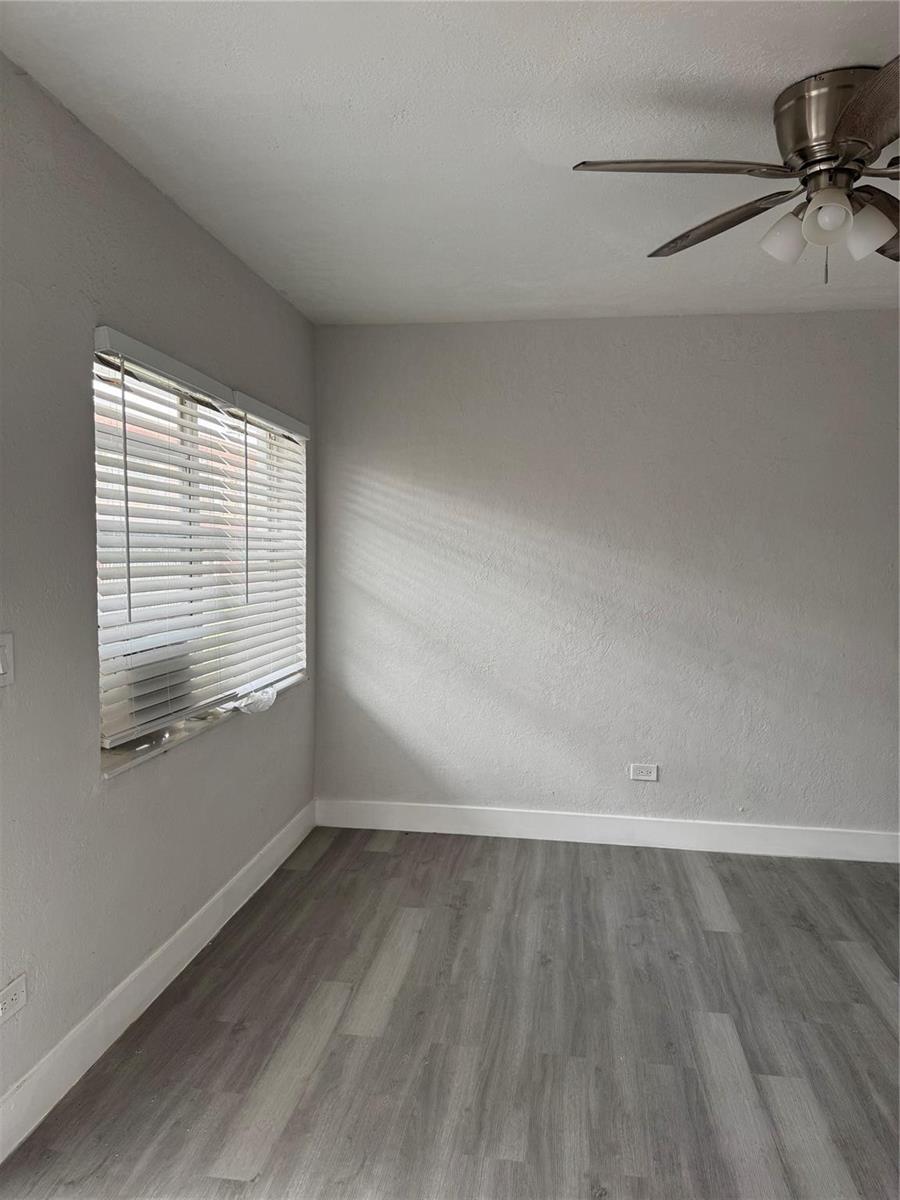 An empty room features gray walls, wood-look flooring, a ceiling fan, and a window with blinds — 731 NW 56th Street, Miami FL 33127, MIAMI, FL