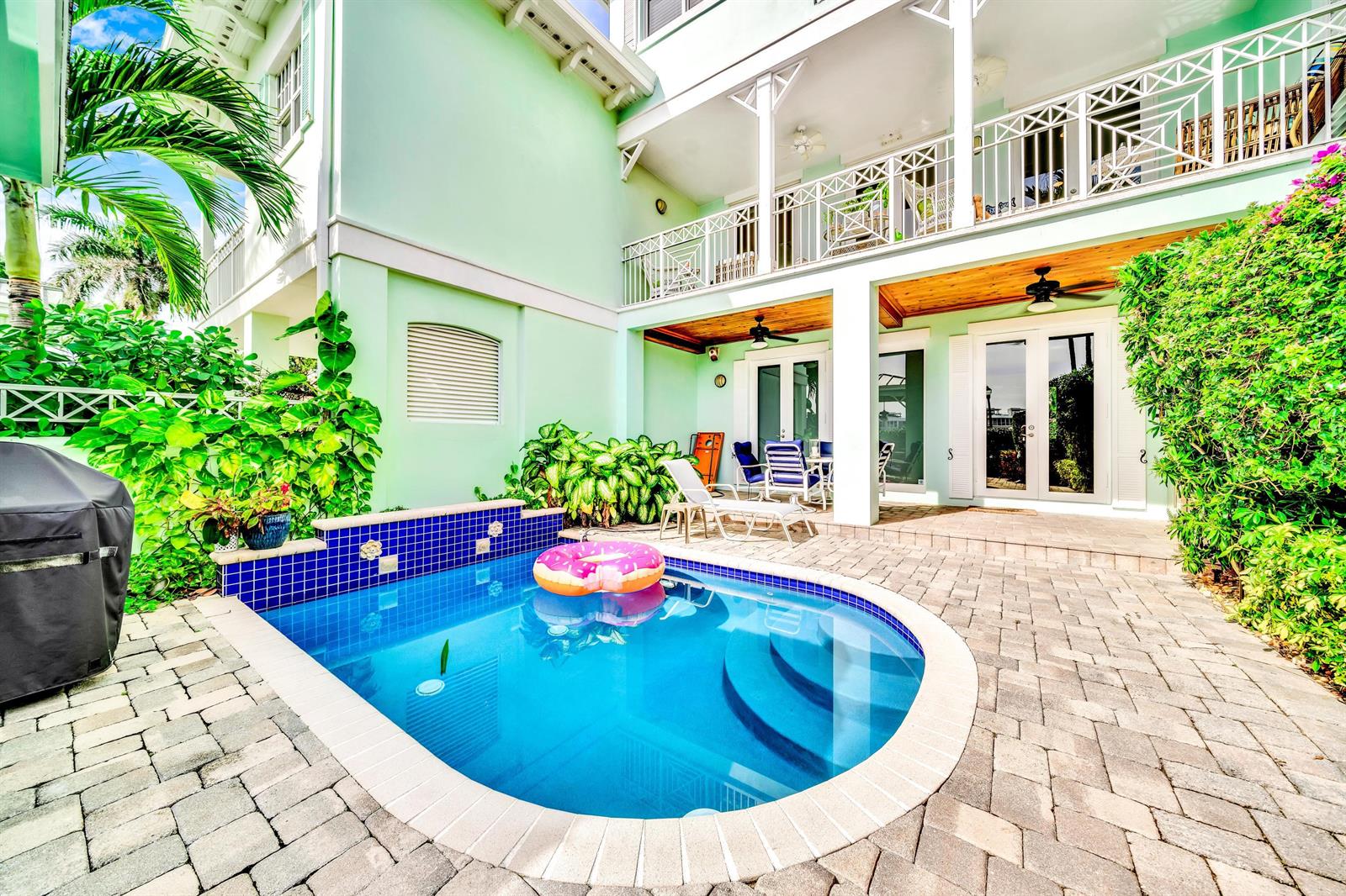 A small backyard pool with a donut float sits on a paved patio by a house — 138 Marine Way, Delray Beach FL 33483, DELRAY BEACH, FL