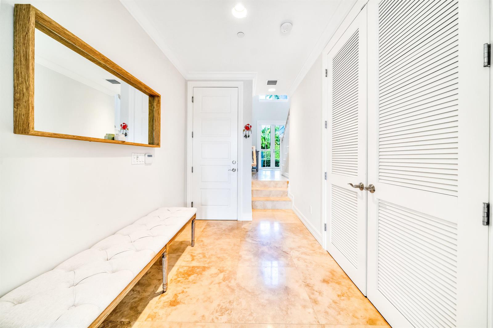 A bright entryway features a tufted bench, a wooden-framed mirror, and white louvered closet doors — 138 Marine Way, Delray Beach FL 33483, DELRAY BEACH, FL