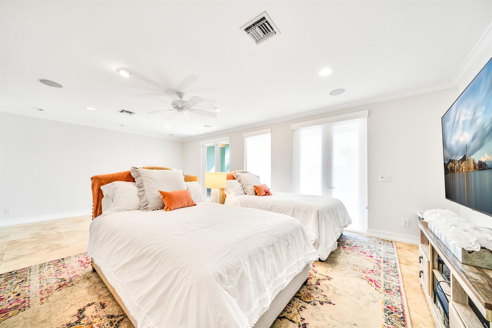 A bedroom features two beds, a television, and a patterned rug on tile flooring — 138 Marine Way, Delray Beach FL 33483, DELRAY BEACH, FL