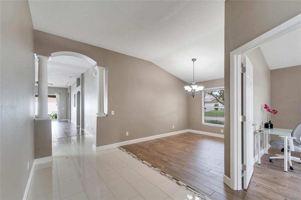 A dining area with wood-look tile floors and a chandelier sits beside a tiled entryway — 12739 STANDBRIDGE DRIVE, RIVERVIEW, FL