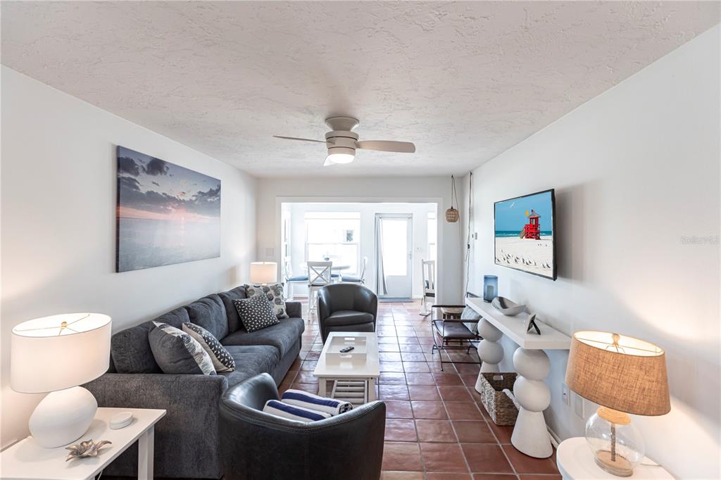A living room features a gray sofa, two armchairs, a television, and terracotta tile flooring — 6020 MIDNIGHT PASS ROAD UNIT 48, SARASOTA, FL