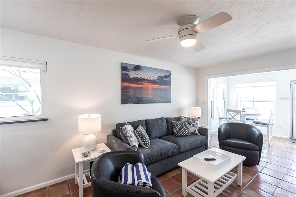 A living room features a dark gray sofa, two black armchairs, and tile flooring — 6020 MIDNIGHT PASS ROAD UNIT 48, SARASOTA, FL