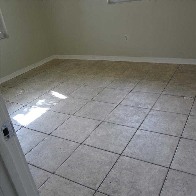 An empty room with light-colored square floor tiles and beige walls — 520 W ELLA J GILMORE STREET, APOPKA, FL