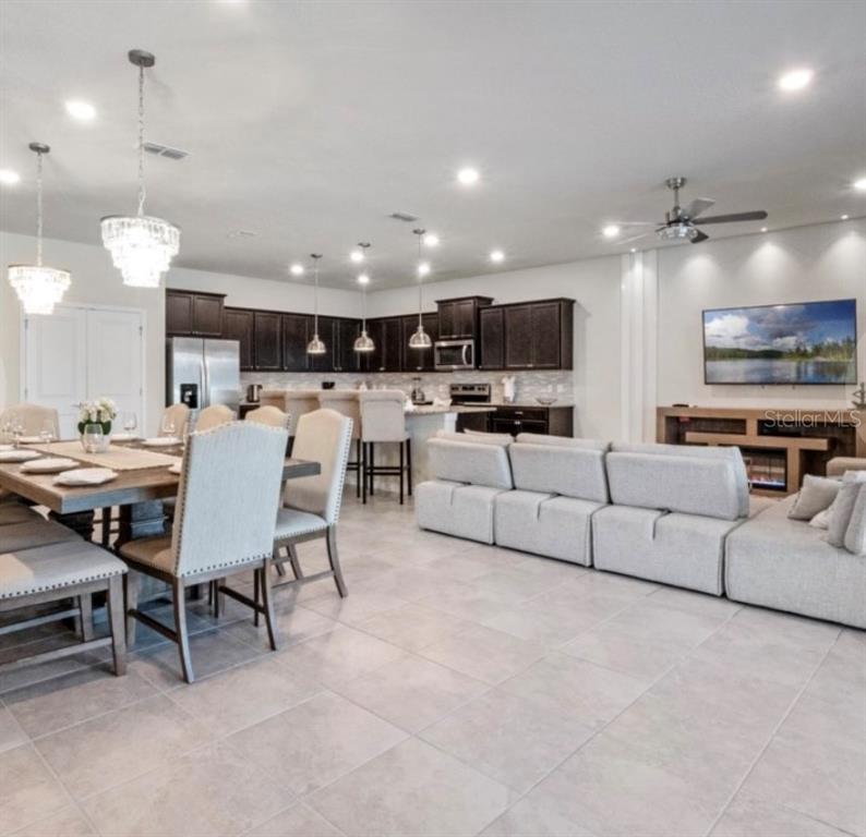 An open-concept kitchen and living area featuring dark cabinetry, a dining table, and light furniture — 2031 LELANI CIRCLE, DAVENPORT, FL