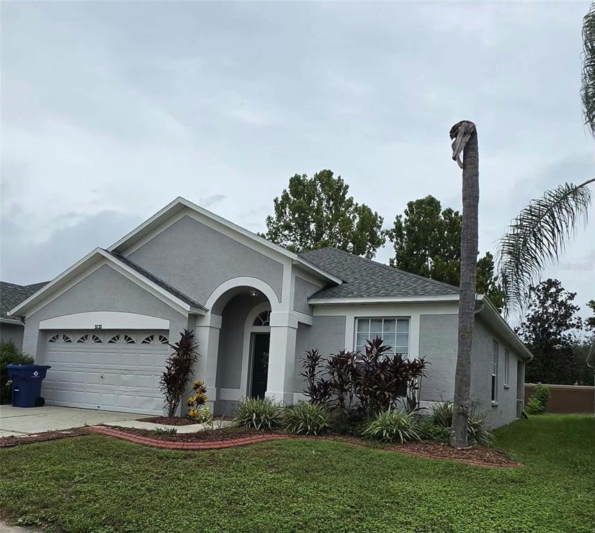 A single-story gray house with a two-car garage and a tall, bare palm tree — 3233 DOWNAN POINT DRIVE, LAND O LAKES, FL