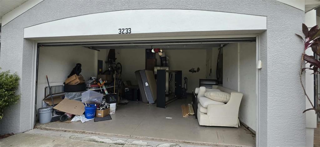 A cluttered residential garage with a white sofa, mattress, and various boxes and items inside — 3233 DOWNAN POINT DRIVE, LAND O LAKES, FL