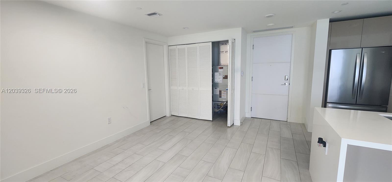 A room with light-colored tile flooring, a white door, and an open utility closet — 2000 Metropica Way # 2106, Sunrise FL 33323, SUNRISE, FL