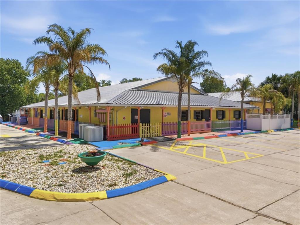 A yellow commercial building with a metal roof and colorful fencing stands in a parking lot — 1330 KNOX MC RAE DRIVE UNIT 6A, TITUSVILLE, FL