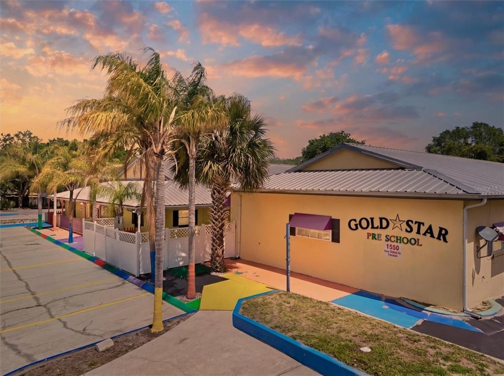 An exterior view of a yellow preschool building with palm trees and a parking lot — 1330 KNOX MC RAE DRIVE UNIT 6A, TITUSVILLE, FL
