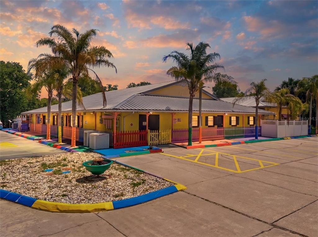 A yellow one-story building with a metal roof and a colorful picket fence exterior — 1330 KNOX MC RAE DRIVE UNIT 6A, TITUSVILLE, FL