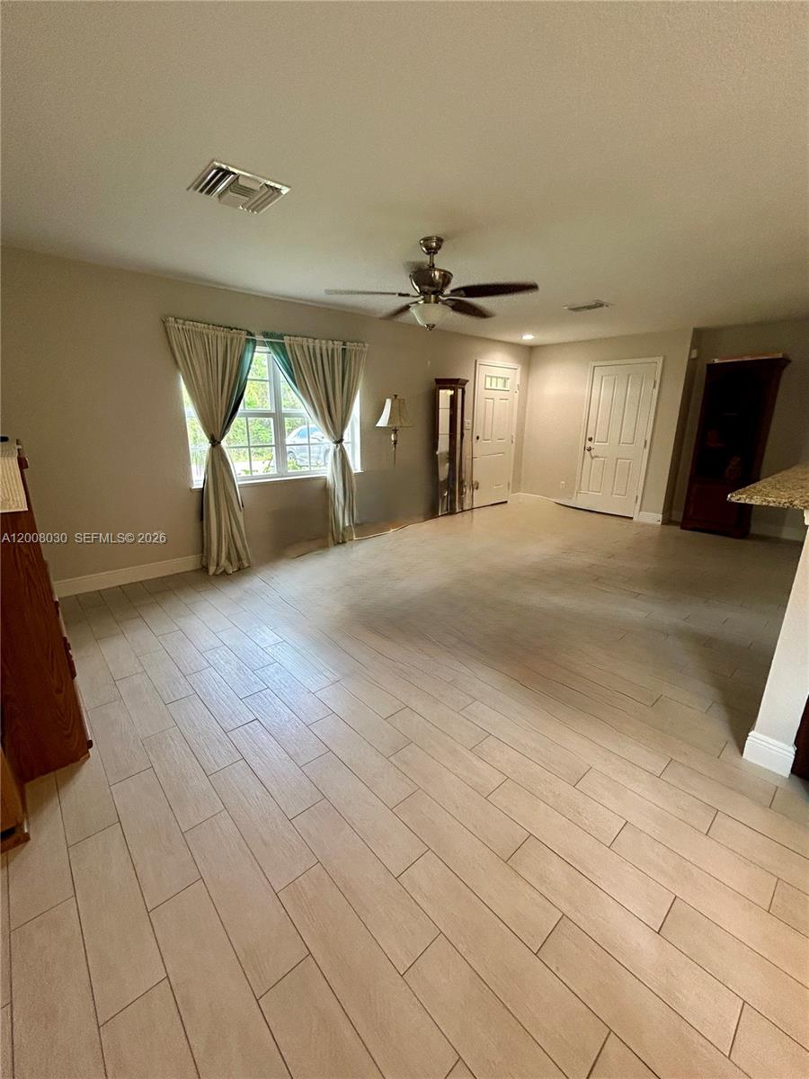 A spacious room features light-colored wood-look tile flooring, a ceiling fan, and two white doors — 358 Lime Rd NW, Lake Placid FL 33852, LAKE PLACID, FL