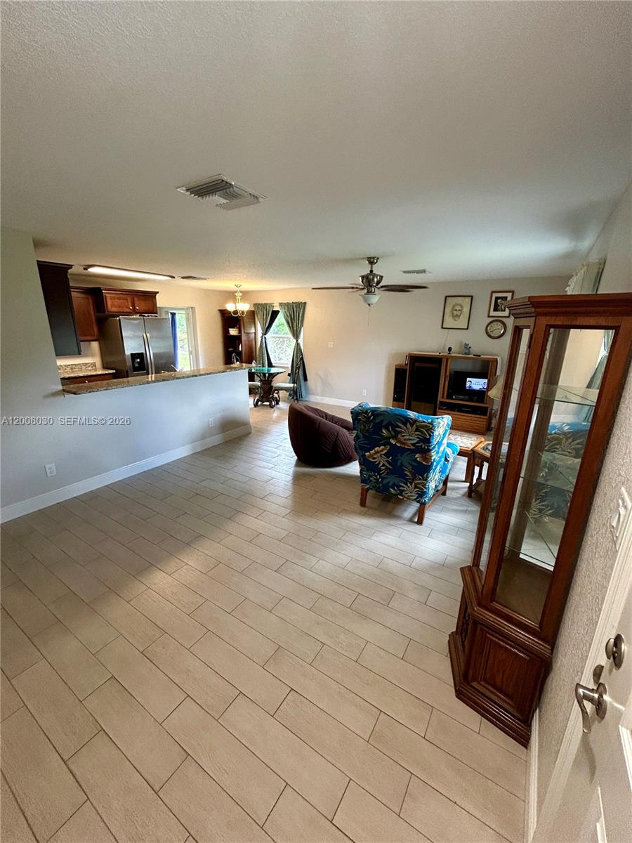 An open-concept living room and kitchen feature light tile flooring and a ceiling fan — 358 Lime Rd NW, Lake Placid FL 33852, LAKE PLACID, FL