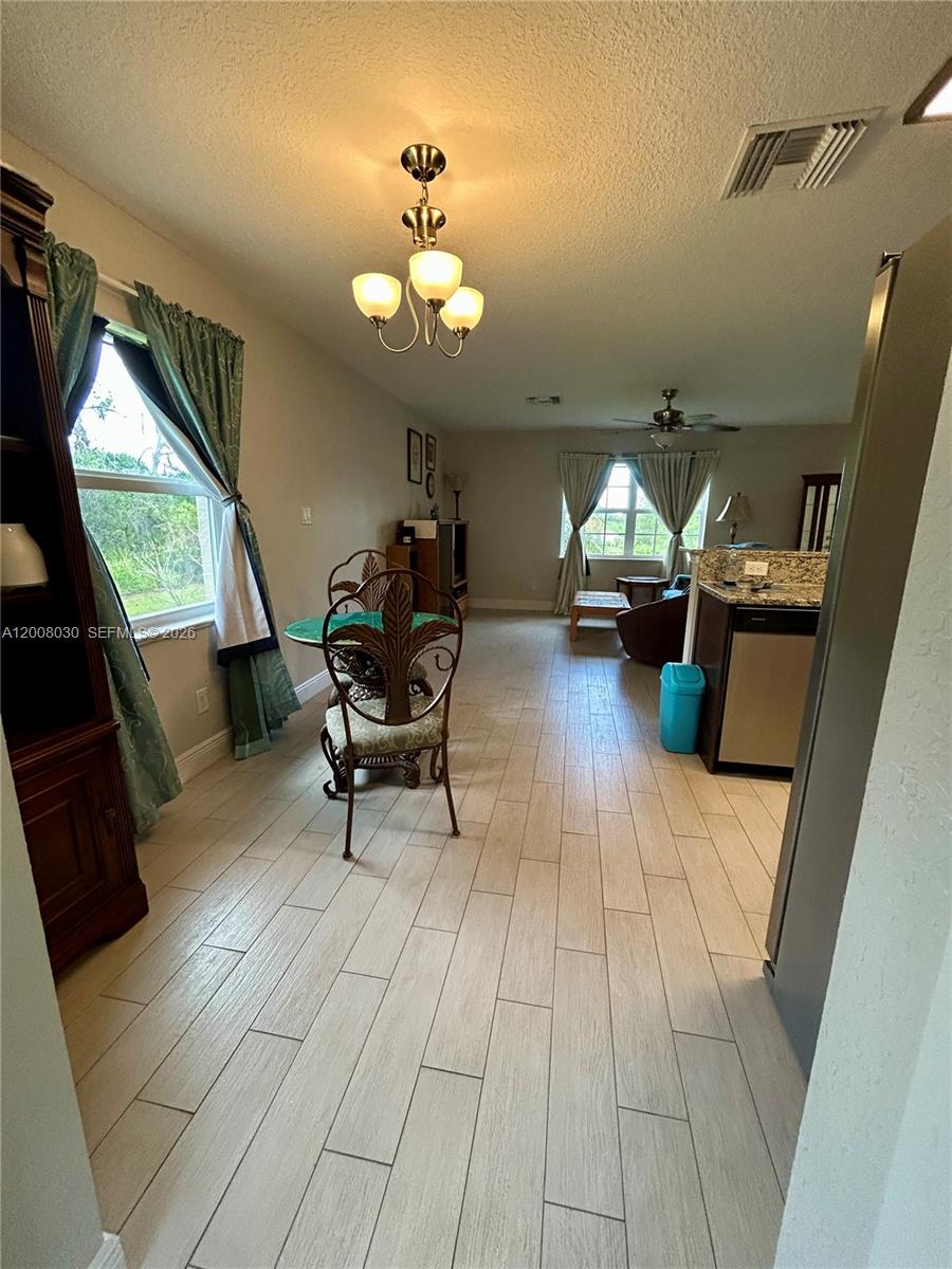 A dining area with wood-look tile flooring flows into a living room with large windows — 358 Lime Rd NW, Lake Placid FL 33852, LAKE PLACID, FL