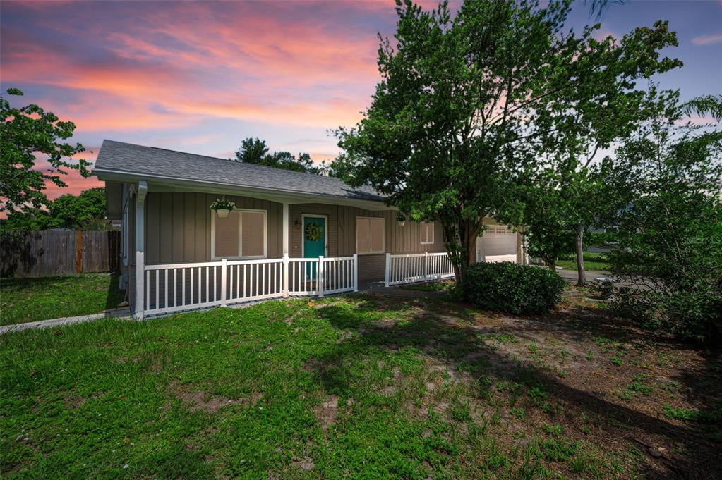 A single-story house with vertical siding, a front porch, and a teal door at sunset — 11501 119TH TERRACE, LARGO, FL
