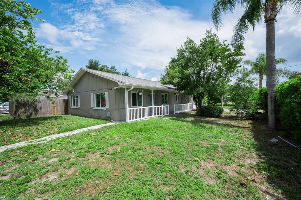 A single-story house with gray siding, a white porch railing, and a grassy front yard — 11501 119TH TERRACE, LARGO, FL