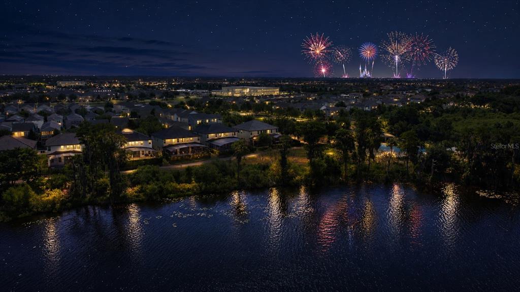 An aerial view of a residential neighborhood at night with fireworks visible in the distance — 8394 LOOKOUT POINTE DRIVE, WINDERMERE, FL