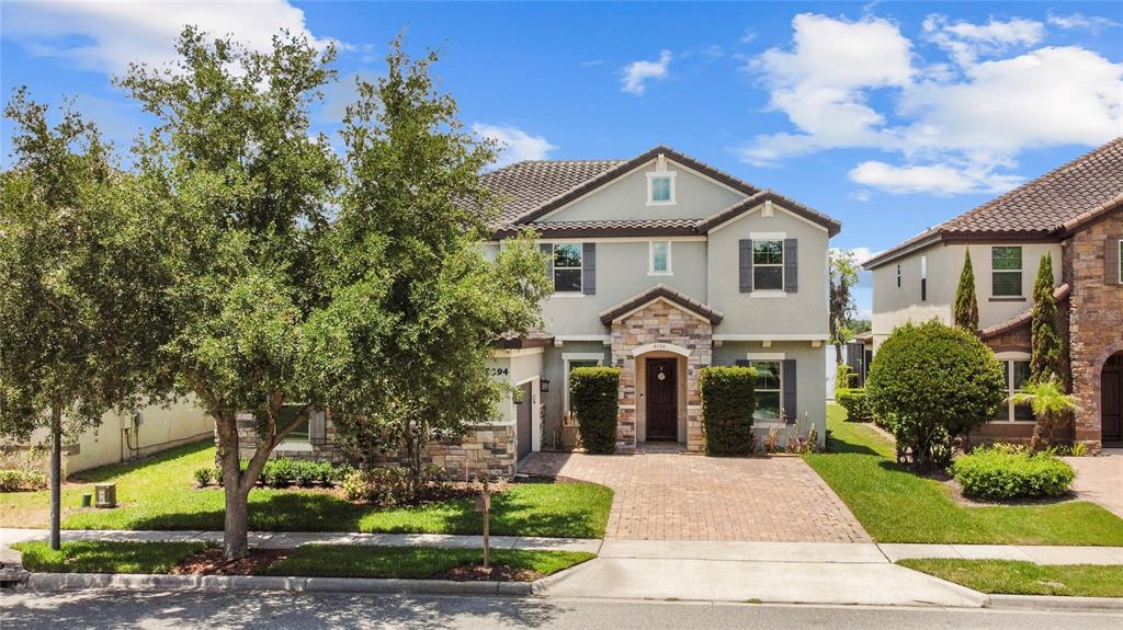 A two-story suburban house features a stone-accented entryway, a paved driveway, and mature landscaping — 8394 LOOKOUT POINTE DRIVE, WINDERMERE, FL